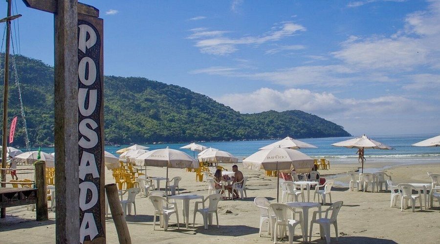 Mesas e guarda-sóis na areia em frente à Pousada Maanaim 1