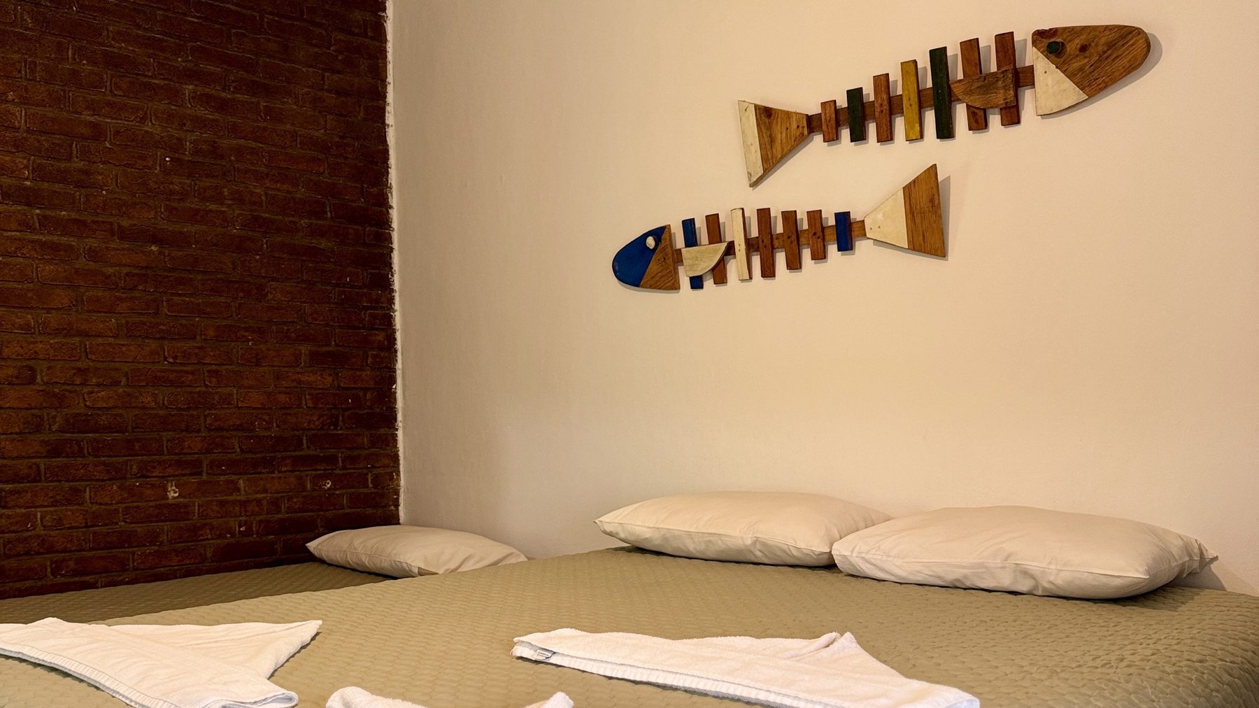 Detalhe do quarto com parede de tijolinho e peixes de madeira