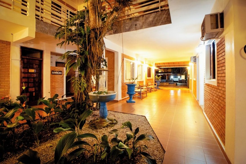 Pátio interno com jardim e fonte, iluminado à noite